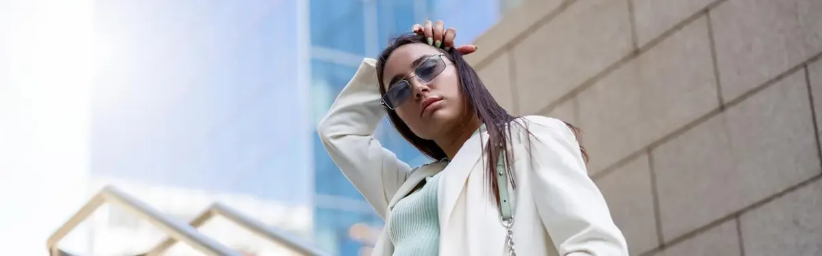 Donna giovane e sicura di sé in un outfit elegante e moderno in un contesto urbano, a simboleggiare lo stile e la professionalità nel mondo della moda